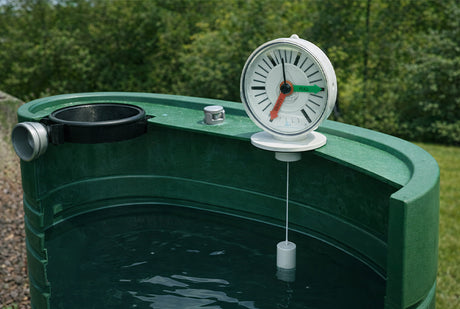 Green water tank with a thermometer on top, set against a blurred green outdoor background.